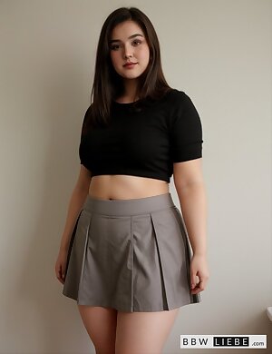 a bbw woman in a black top and a gray skirt is posing for a picture with her hands on her hips and she is wearing a black crop top and